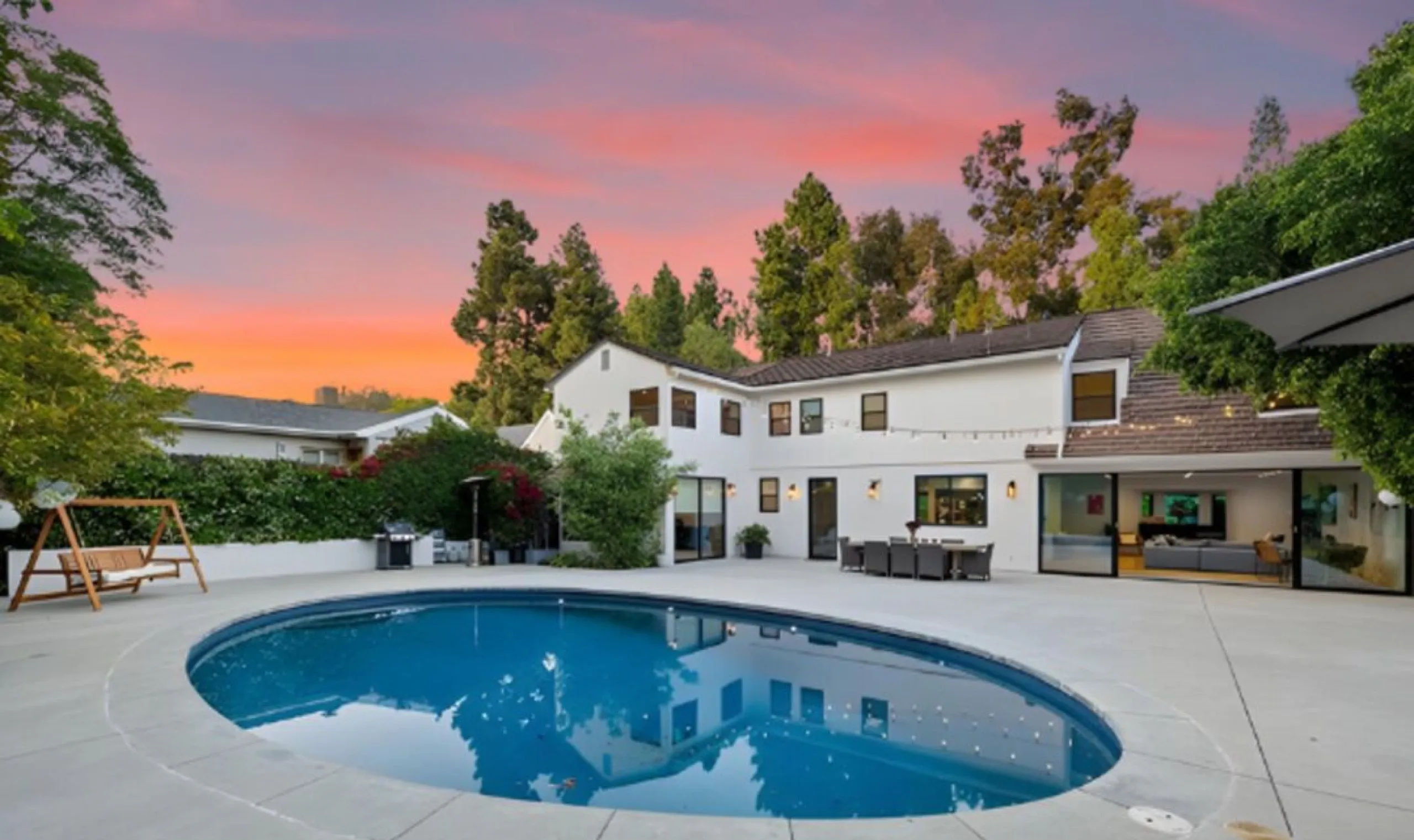 Oval pool and patio at dusk behind the Westwood residence at 343 Veteran Avenue