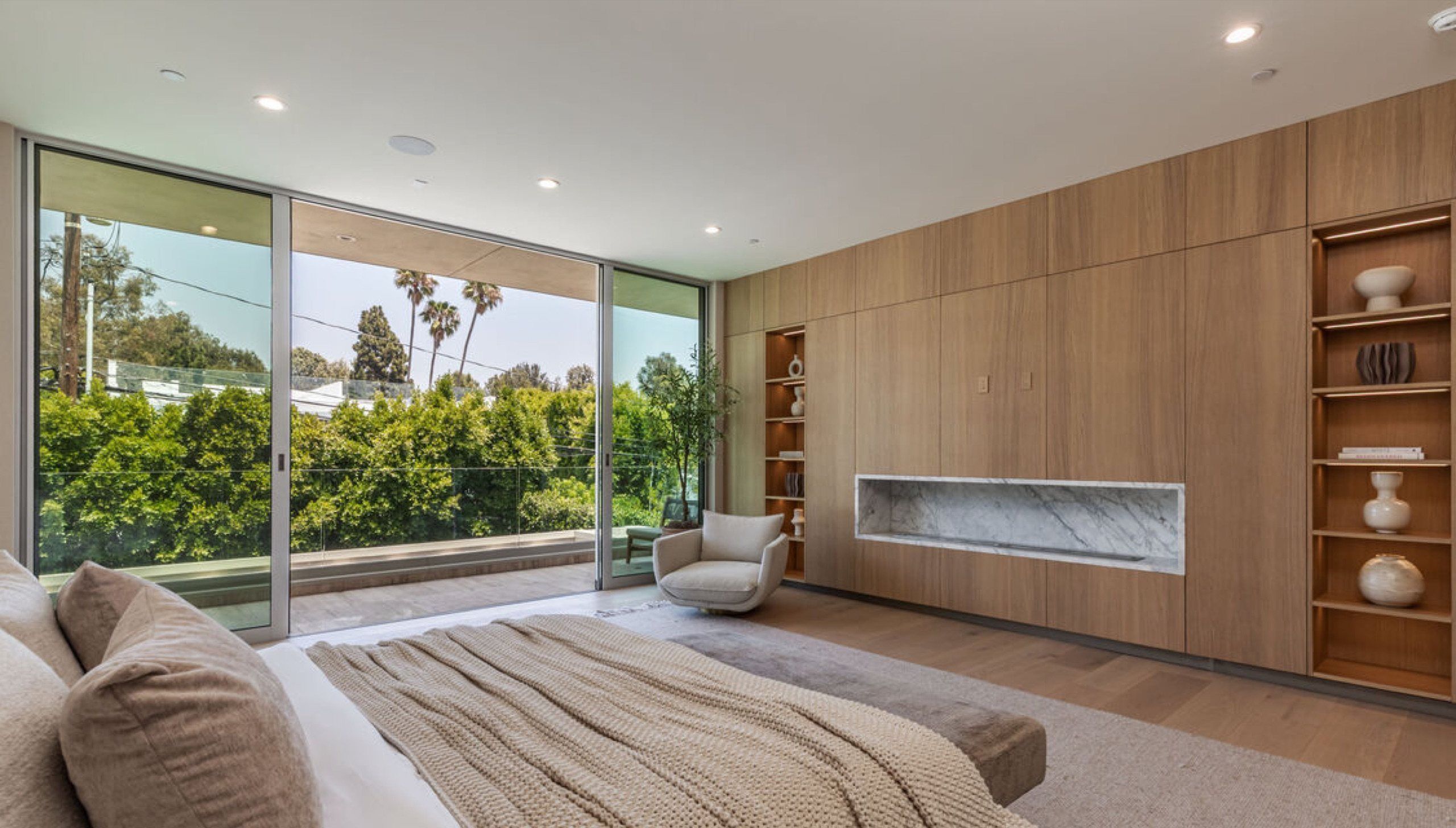 Primary bedroom with marble fireplace and floor to ceiling glass